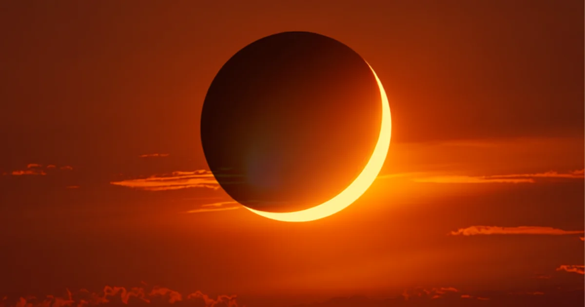 Croissant de l'éclipse solaire du 12 août 2026 dans un ciel orange de fin de journée