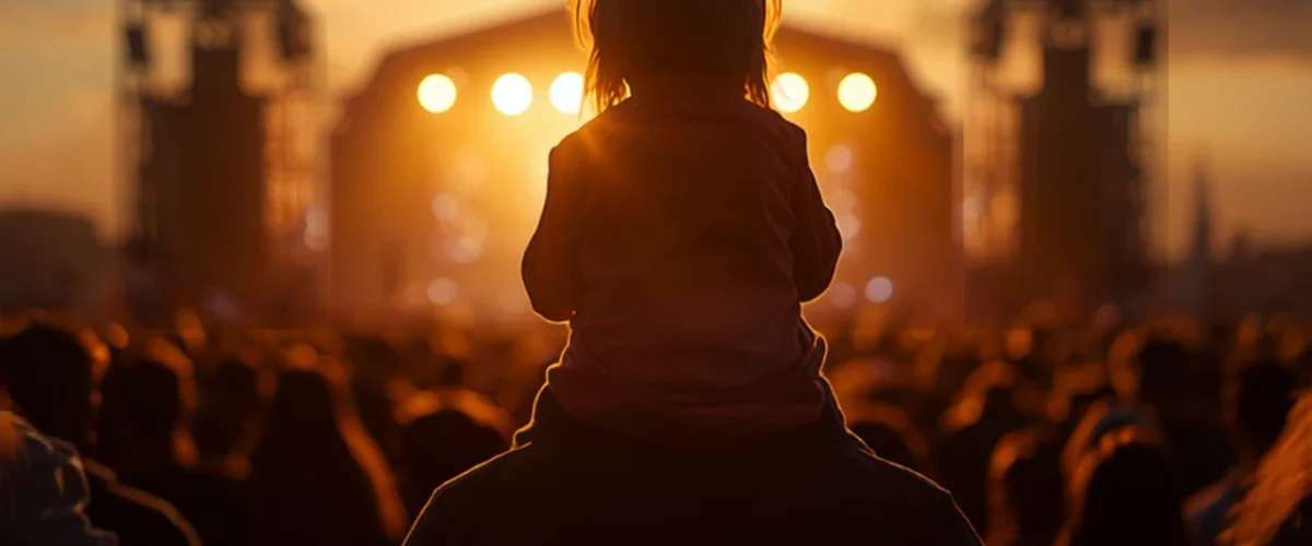 Enfant sur les épaules d'un adulte face à la scène du Festidreuz à Fouesnant au coucher du soleil