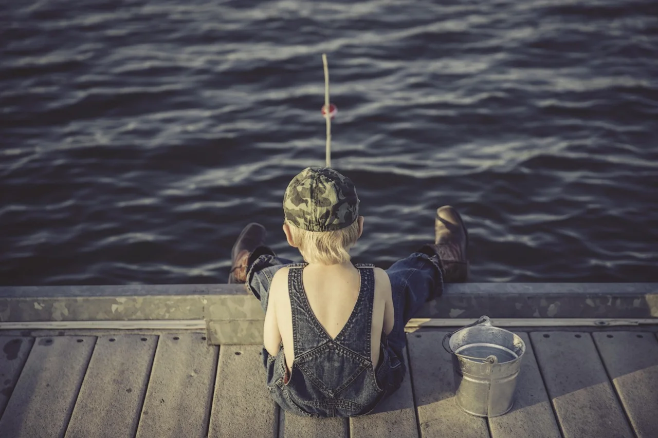Enfant de dos assis au bord d’un ponton, illustration de portrait avec effet de profondeur de champ