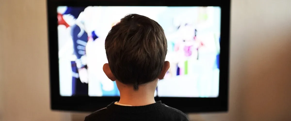 Garçon de dos devant la télévision, illustration de la règle des 2 heures d'écran par jour