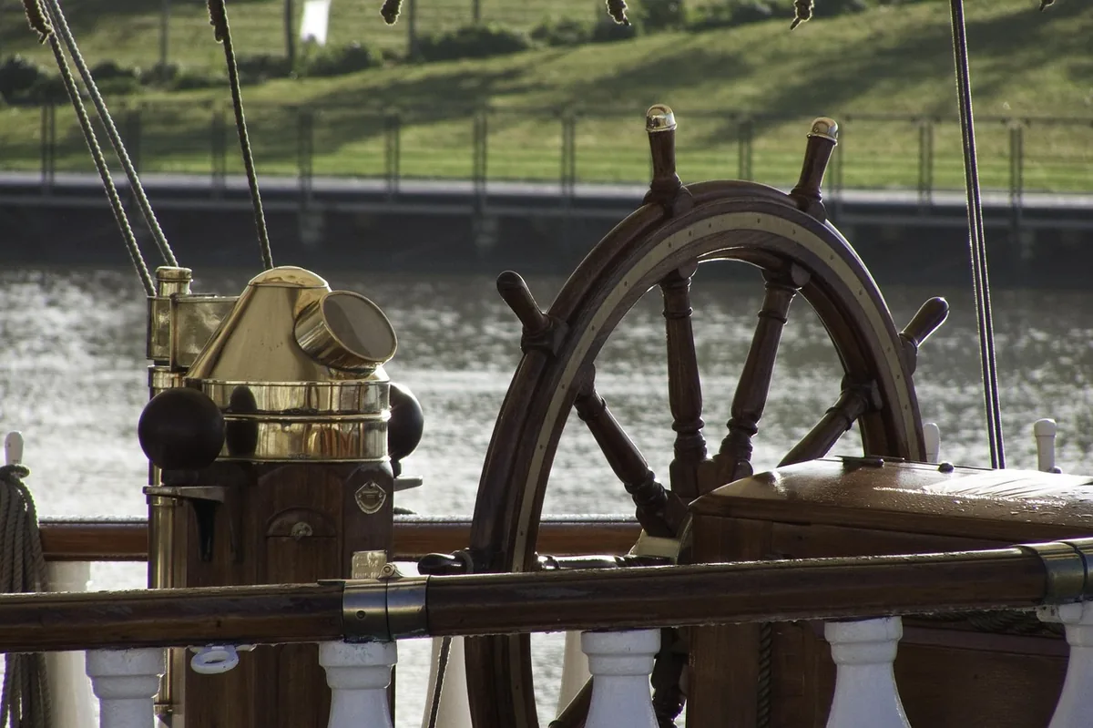 La barre à roue en bois et le compas de route en laiton du trois-mâts Belem
