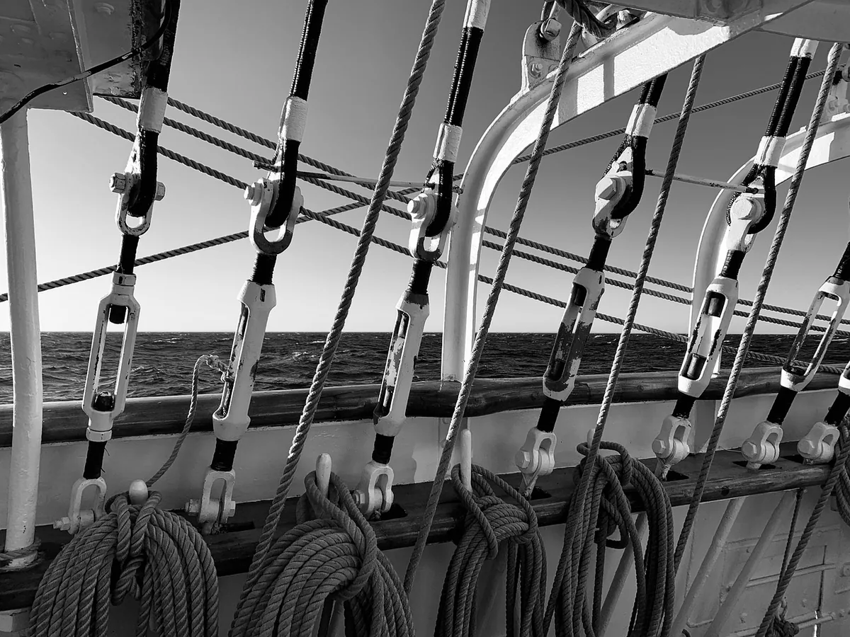 Le pont du trois-mâts Belem en noir et blanc, cordages et gréement face à la mer