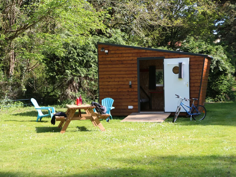 Une cabane RandoCabane dans l'herbe, avec table de pique-nique et vélo, à Saint-Fiacre-sur-Maine