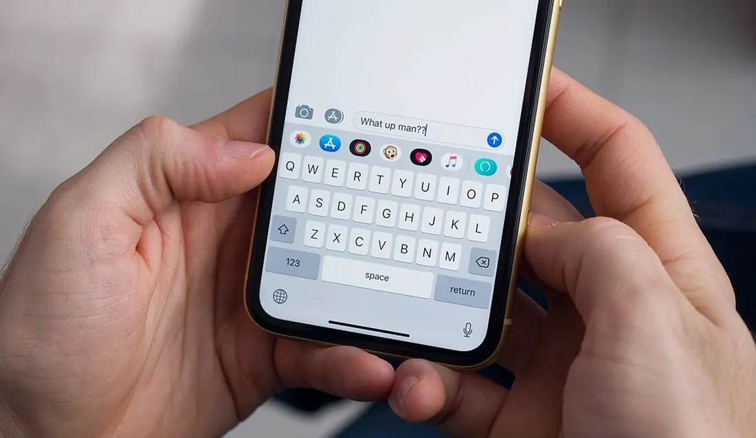 Mains qui tapent un message sur iPhone pour garder le contact