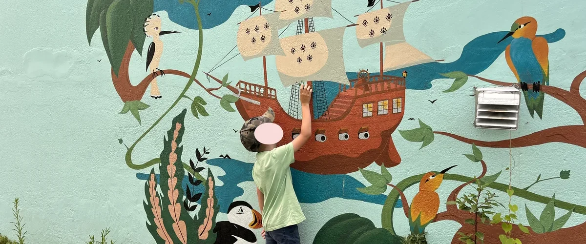 Sortie à Trentemoult en famille : un enfant observe une fresque murale de bateau pirate